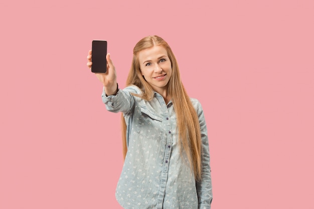 Portret ufna przypadkowa dziewczyna pokazuje pustego ekranu telefon komórkowego odizolowywającego nad menchii ścianą