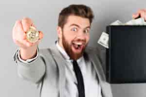 Bezpłatne zdjęcie portret ufny biznesmen pokazuje złotego bitcoin