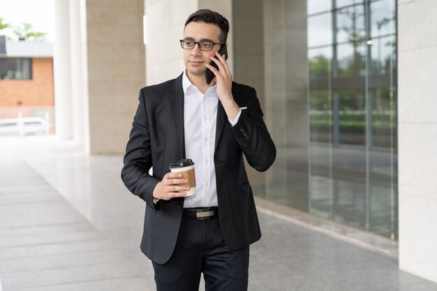 Portret ufny młody biznesmen opowiada na telefonie komórkowym