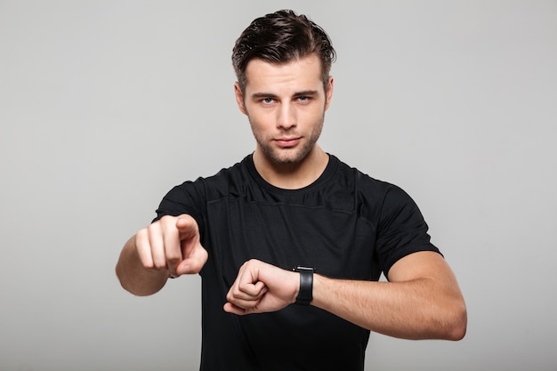 Portret ufny młody sportowiec pokazuje jego wristwatch