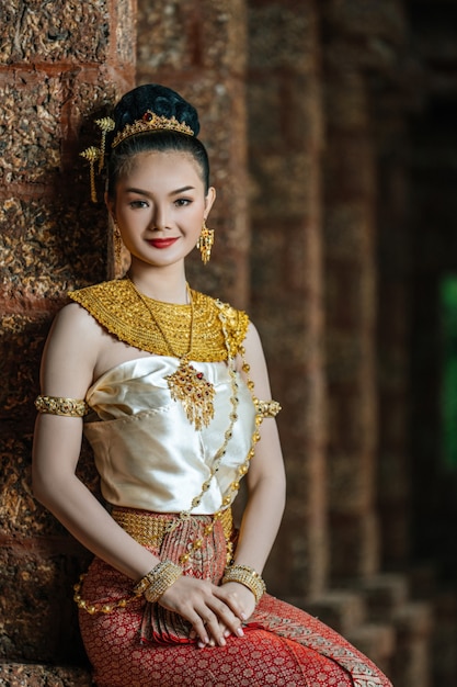 Portret urocza tajska kobieta w pięknym tradycyjnym stroju, kobieta ubrana w typową tajską sukienkę siedzącą na stanowisku archeologicznym lub tajlandzkiej świątyni, kultura tożsamości Tajlandii