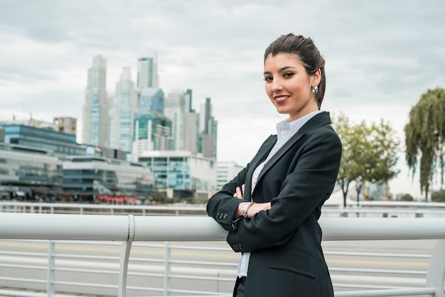 Portret uśmiechnięta bizneswoman pozycja przed pejzażem miejskim