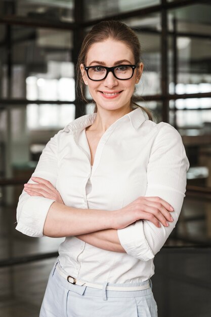 Portret uśmiechnięta bizneswoman w pomieszczeniu z zamkniętymi rękami