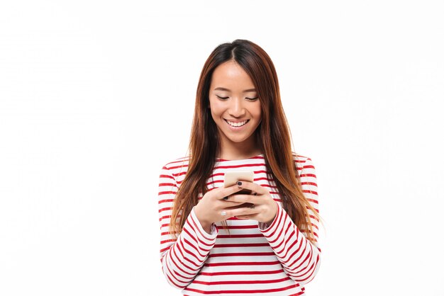 Portret uśmiechnięta młoda azjatykcia dziewczyna używa telefon komórkowego