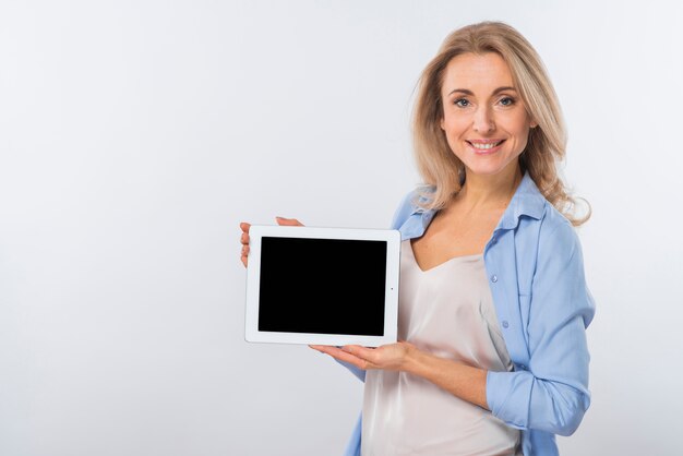 Portret uśmiechnięta młoda kobieta pokazuje cyfrową pastylkę przeciw białemu tłu