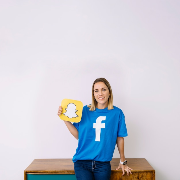Portret uśmiechnięta młoda kobieta trzyma snapchat logo