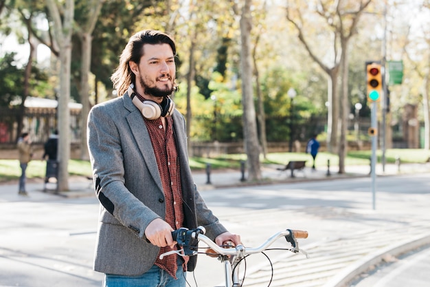 Portret uśmiechnięta młody człowiek pozycja z bicyklem na drodze