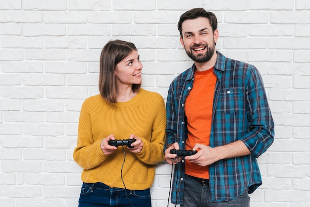 Bezpłatne zdjęcie portret uśmiechnięta potomstwo para bawić się wideo grę z konsolą