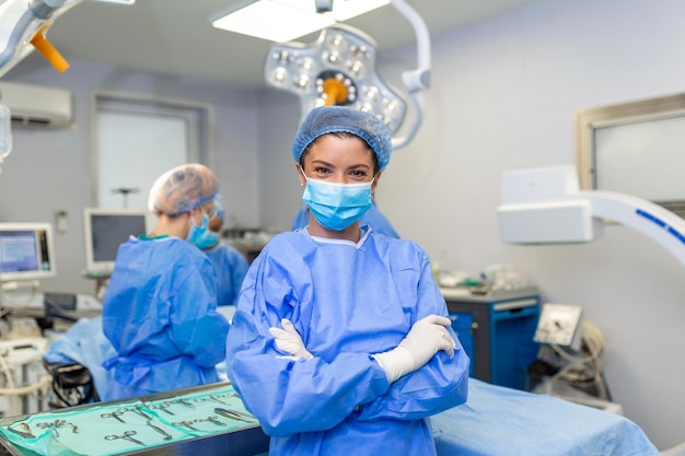 Portret uśmiechniętego chirurga w szpitalu Kobieta pracownik służby zdrowia ma na sobie fartuch. Stoi ze skrzyżowanymi rękami przed światłem