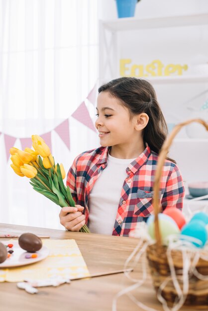 Portret uśmiechniętego małej dziewczynki mienia żółty tulipan kwitnie na Easter dniu