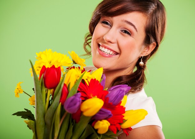 Portret uśmiechniętej kobiety z kolorowymi kwiatami