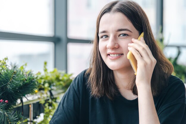 Portret uśmiechniętej młodej kobiety rozmawiającej przez telefon