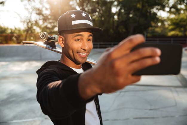 Portret uśmiechnięty afrykański męski nastolatek bierze selfie