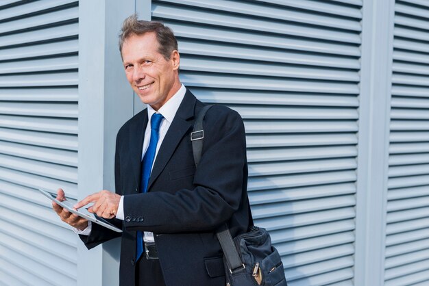 Portret uśmiechnięty dojrzały biznesmen używa cyfrową pastylkę