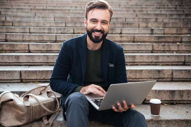 Portret uśmiechnięty mężczyzna pracuje na laptopie