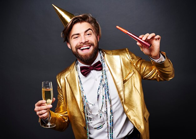 Portret uśmiechnięty mężczyzna trzyma flet szampana i dmuchawy strony