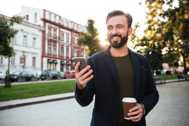 Portret uśmiechnięty młodego człowieka mienia telefon komórkowy