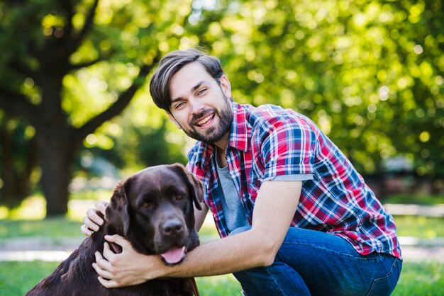 Portret uśmiechnięty młody człowiek i jego pies w parku