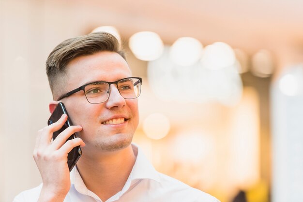 Portret uśmiechnięty młody człowiek opowiada na telefonie komórkowym