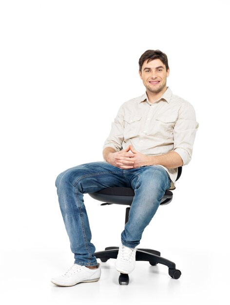 Portret uśmiechnięty szczęśliwy mężczyzna siedzi na krześle na białym tle.