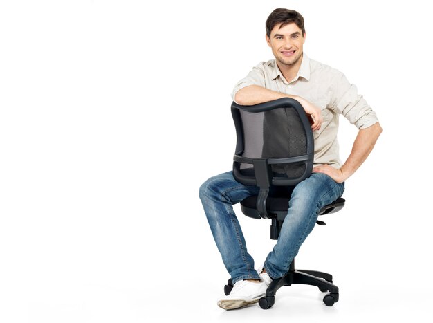 Portret uśmiechnięty szczęśliwy mężczyzna siedzi na krześle na białym tle.