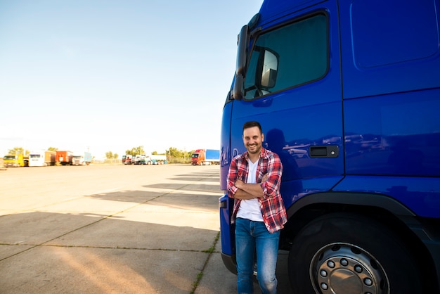 Bezpłatne zdjęcie portret uśmiechnięty trucker stojący przy jego ciężarówce gotowy do jazdy