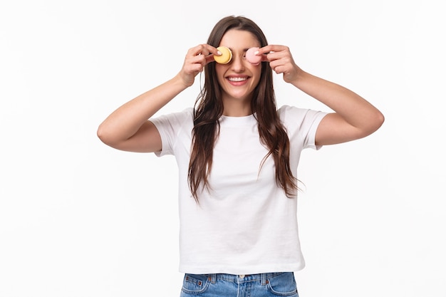 Portret w pasie zabawne i słodkie, urocze, młode kobiety trzymającej dwa desery macarons