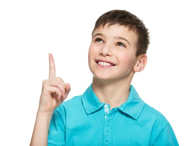 Portret wesoły chłopiec nastolatek wskazując palcem w górę - na białym tle nad białym