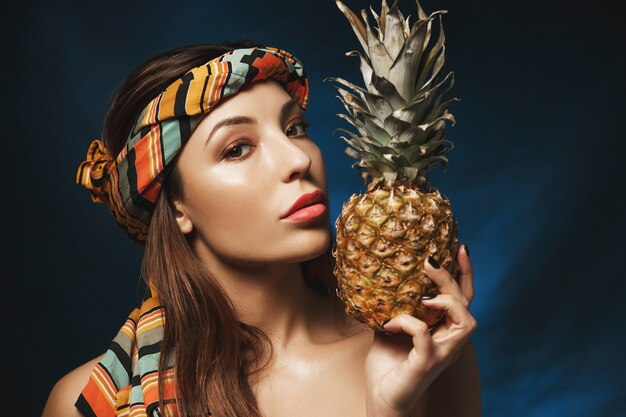 Portret Wspaniała kobieta z kolorowymi bandanami na głowie, trzyma ananasa.