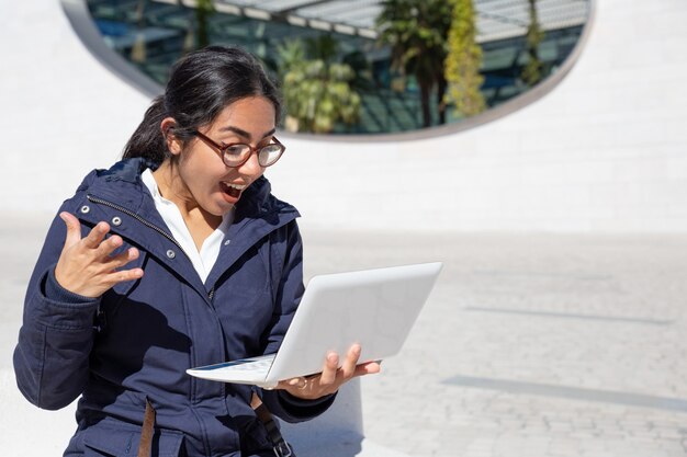Portret z podnieceniem młoda kobieta używa laptop outdoors