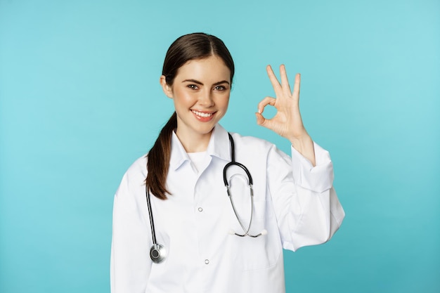 Portret zadowolonej uśmiechniętej pracowniczki medycznej kobiety lekarki pokazującej w porządku ok zero bez problemu gest ex...