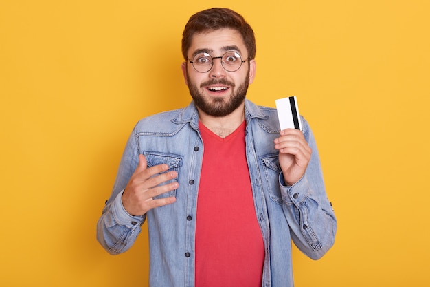 Portret zbliżenie zdumiony brodaty mężczyzna z kartą kredytową w rękach, wygląda na podekscytowanego, dowiedział się o ogromnej ilości pieniędzy na karcie