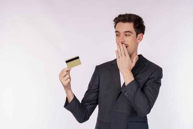 Portret zdziwiony biznesmen pokazujący kartę kredytową odizolowywającą nad białym tłem