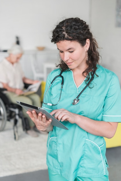 Bezpłatne zdjęcie portret żeńska pielęgniarka z stetoskopem wokoło jej szyi używać cyfrową pastylkę