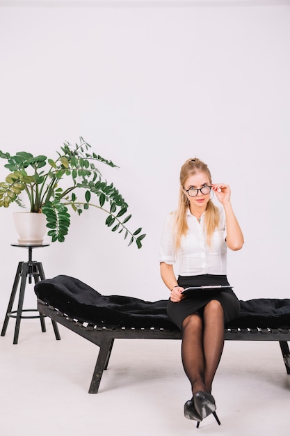 Portret żeński psychologa obsiadanie na leżanki mienia schowku w ręce patrzeje przez eyeglasses