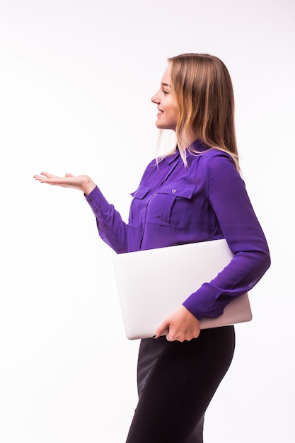 Portret zszokowana szczęśliwa kobieta z laptopem trzymając miejsce na dłoni na białym tle na szarej ścianie