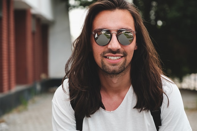 Portreta atrakcyjny mężczyzna z okularami przeciwsłonecznymi na miastowy sceny ono uśmiecha się