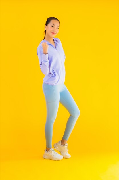 Portreta sporta piękna młoda azjatykcia kobieta przygotowywająca dla ćwiczenia na kolorze żółtym