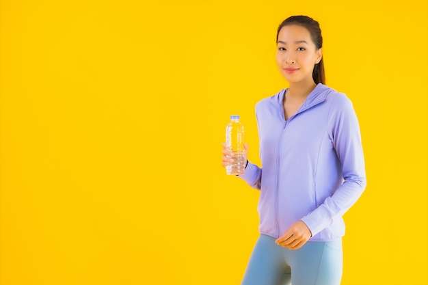 Portreta sporta piękna młoda azjatykcia kobieta przygotowywająca dla ćwiczenia na kolorze żółtym