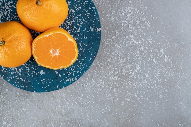 Posyp proszek kokosowy i półmisek pomarańczy na marmurowym stole.