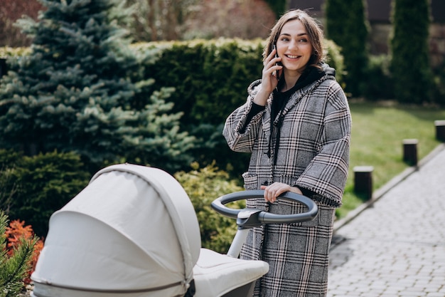 Potomstwa matkują odprowadzenie z wózkiem w parku i rozmawiać przez telefon