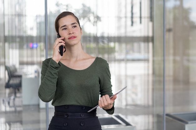 Poważna biznesowa dama skupiająca się na rozmowie telefonicza