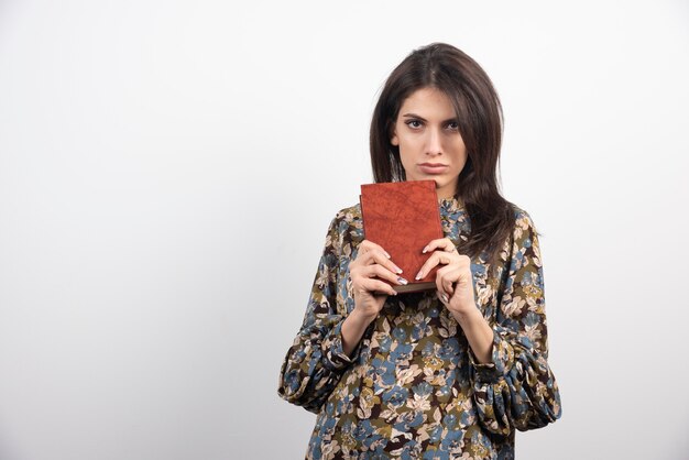 Poważna brunetka kobieta pokazuje książkę.