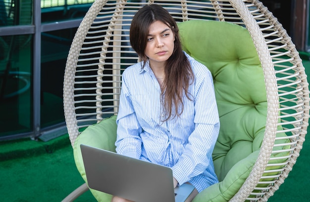 Poważna Młoda Kobieta Pracuje Na Laptopie, Siedząc W Hamaku