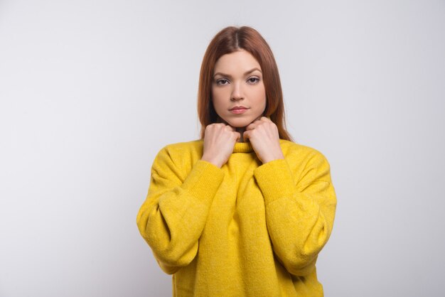 Poważna młoda kobieta w żółtym swetrze