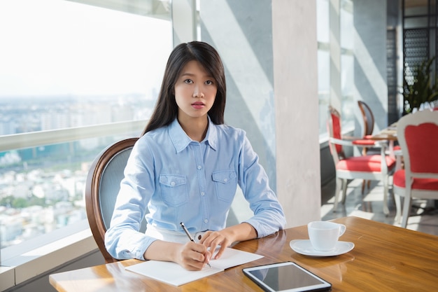 Poważne Young Asian kobieta pisanie w kawiarni