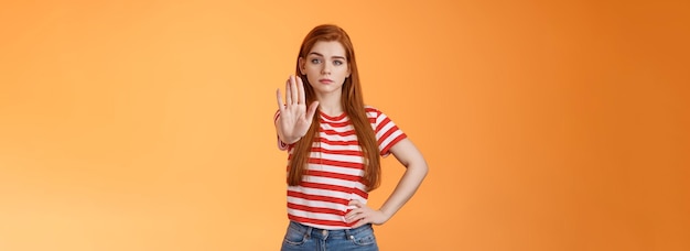 Bezpłatne zdjęcie poważnie wyglądająca, pewna siebie, odważna rudowłosa dziewczyna przeciwstawia się hejterom walczącym o wolność, zakazuje nielegalnych działań
