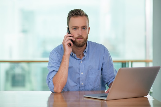 Poważny biznesmen rozmawia przez telefon w biurze