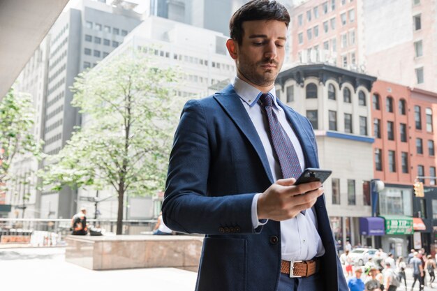 Poważny biznesmen używa smartphone na ulicie