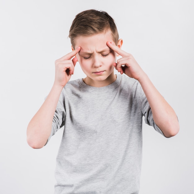 Poważny chłopiec ma ból głowy pozycję przeciw białemu tłu